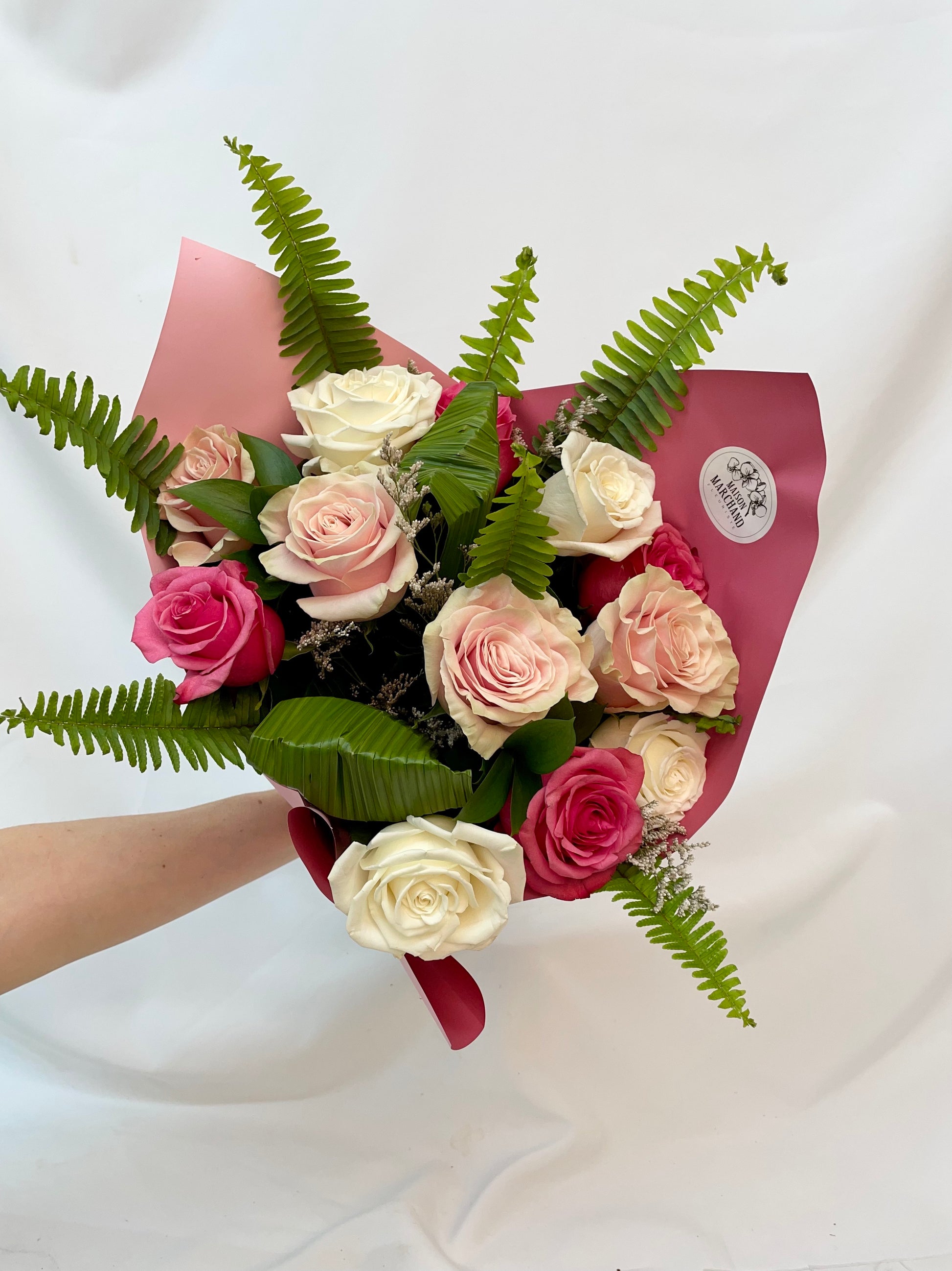 Bouquet de 12 roses dans les tons de rose et blanc, accompagné de feuillage exotique, nommé “Tendre Maman”. Présenté pour la collection “Fête des Mères”.